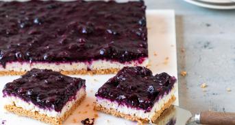 Milchreiskuchen mit Beerentopping angeschnitten auf einer Marmorplatte