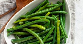 Dampfgegarte grüne Bohne auf einem Teller, daneben ein Schälchen mit grobem Salz