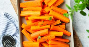 Dampfgegarte Möhrenstücke auf einem rechteckigen Steingutteller dekoriert mit Petersilie