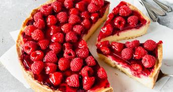 Himbeer-Käsekuchen angeschnitten auf einem Stück Backpapier.