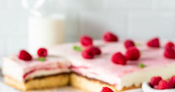 Ein Stück Himbeer-Quark-Torte auf einem Kuchenteller mit angelegter Gabel.