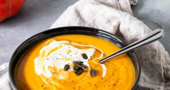 Kürbissuppe mit Ingwer und Kürbiskernen in einem Suppenteller mit Löffel.