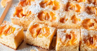 Mandarinenblechkuchen mit halbierten Mandarinen angeschnitten auf einem Tisch