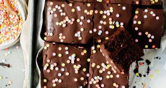 Schokokuchen vom Blech in Stücken mit Glasur und Zuckerstreuseln.