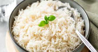 Dampfgegarter Reis in einer Schale, dekoriert mit frischen Kräutern auf einem Tisch