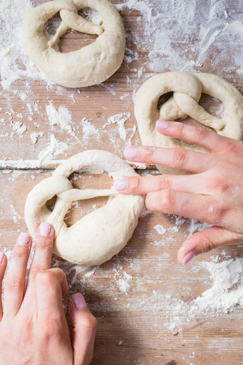 Brezel werden auf einer bemehlten Arbeitsfläche geformt.