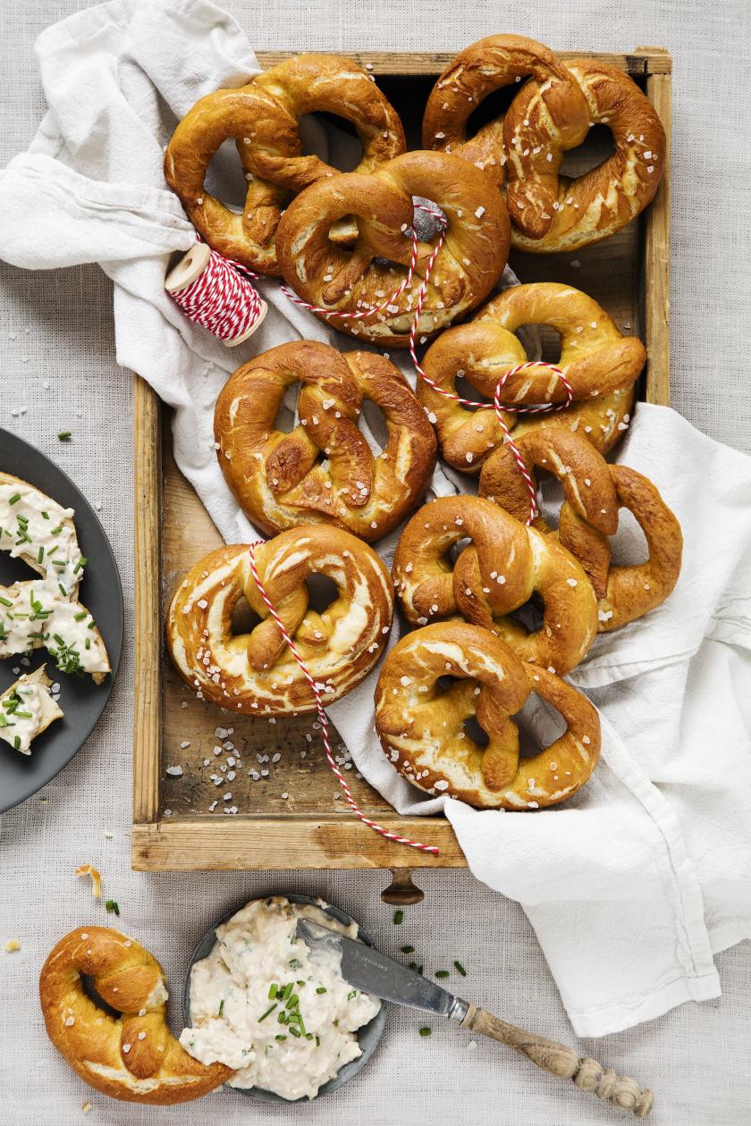 Mehrere Brezel in einer Kiste, daneben Obazda.