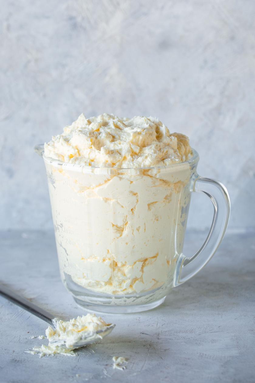 Buttercreme in einem Messbecher mit angelegtem Löffel samt Buttercreme.