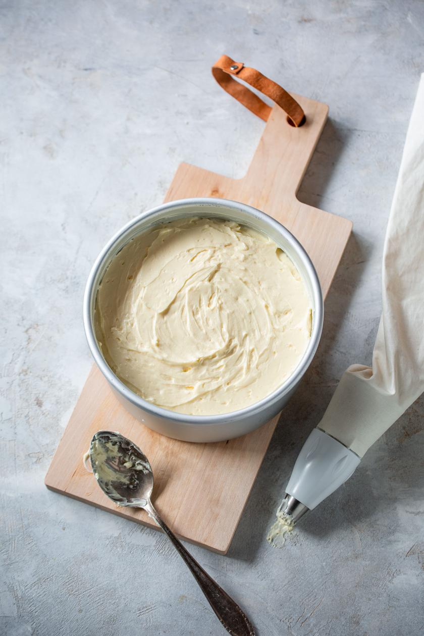 Buttercreme in einer Schale auf einem Holzbrett mit angelegtem Löffel.