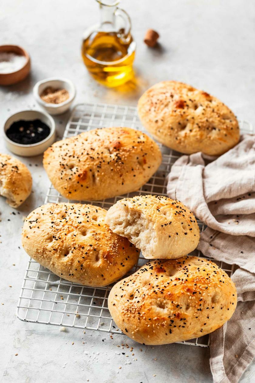 Mini Fladenbrote auf einem Küchengitter, daneben eine Schale mit Olivenöl