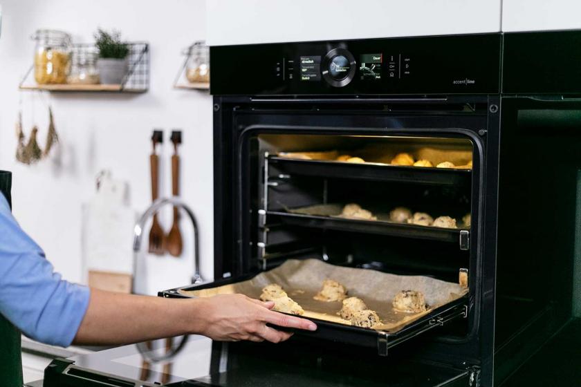 Die American Cookies werden auf einem Blech in den Backofen geschoben.