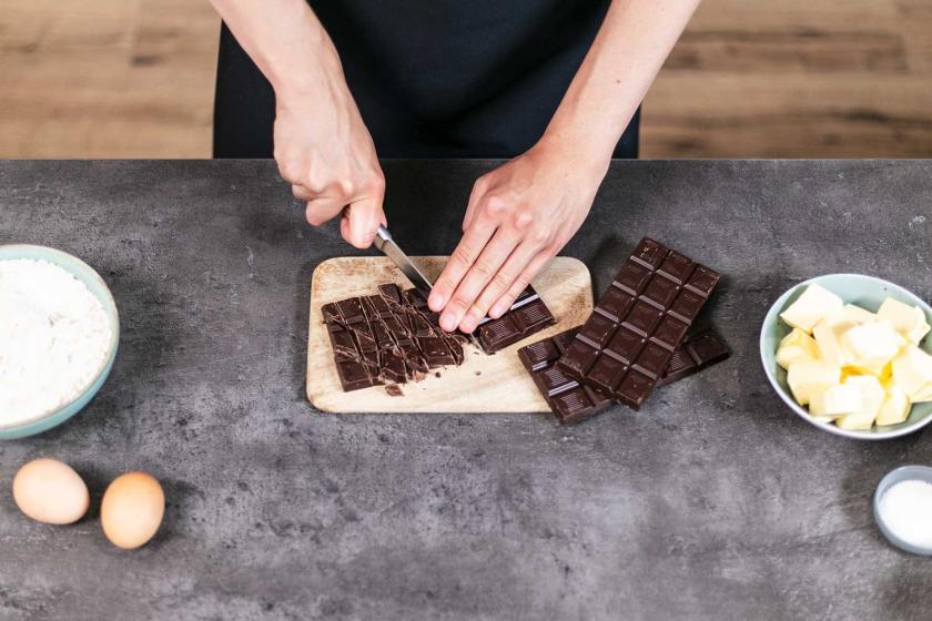 Schokolade fü die American Cookies wird auf einem Holzbrett gehackt.
