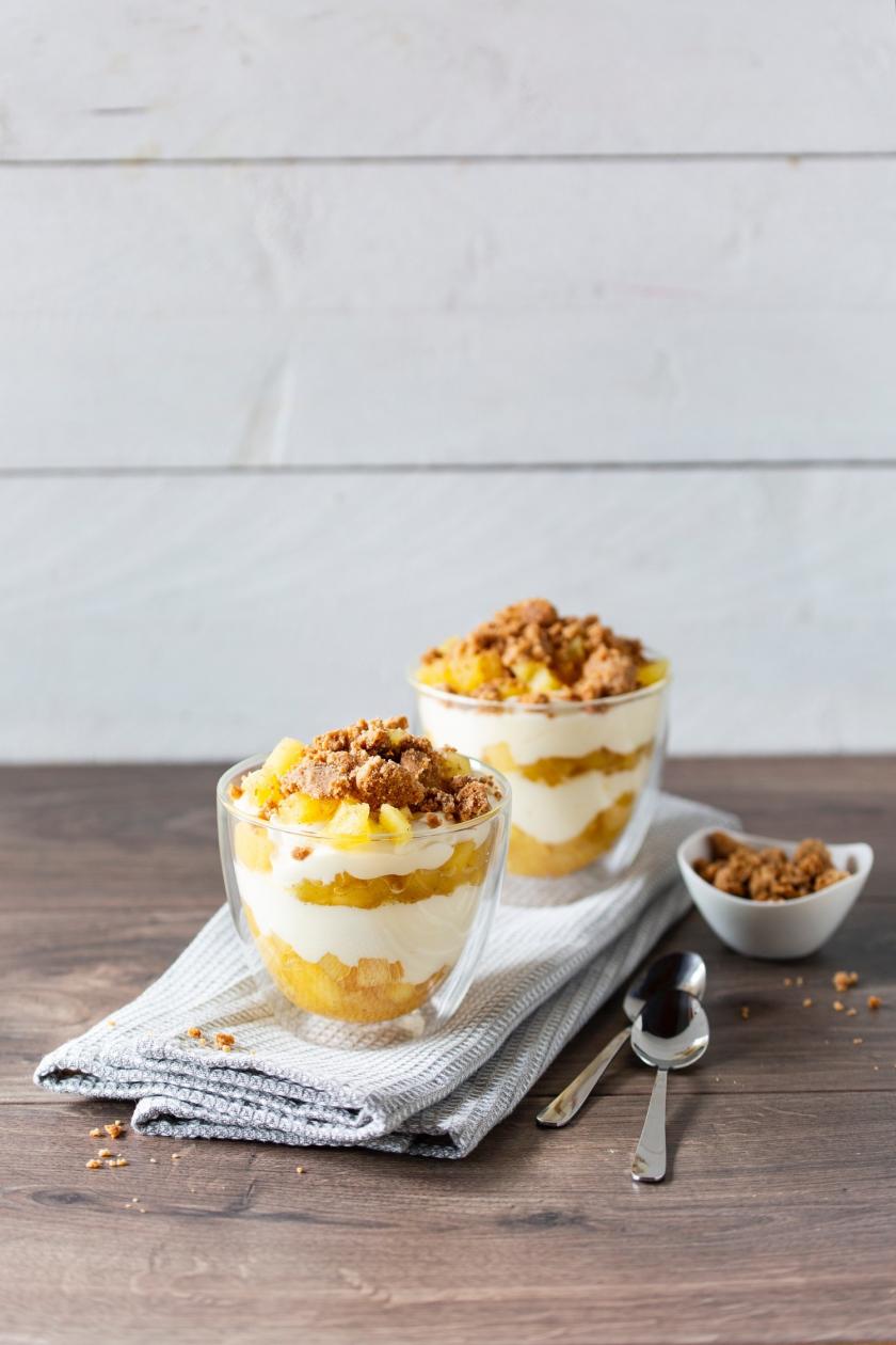 Zwei Apfel-Crumble im Glas auf Küchentuch.