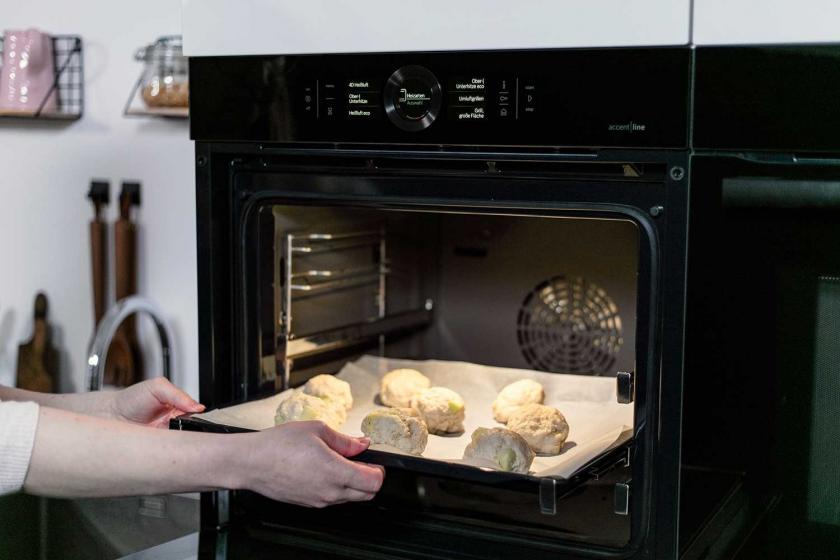 Apfelballen auf einem Blech werden in den Ofen geschoben.