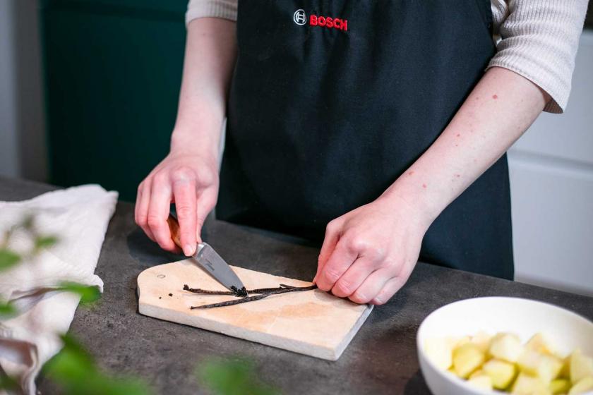 Eine Vanilleschote wird mit einem Messer ausgekratzt.