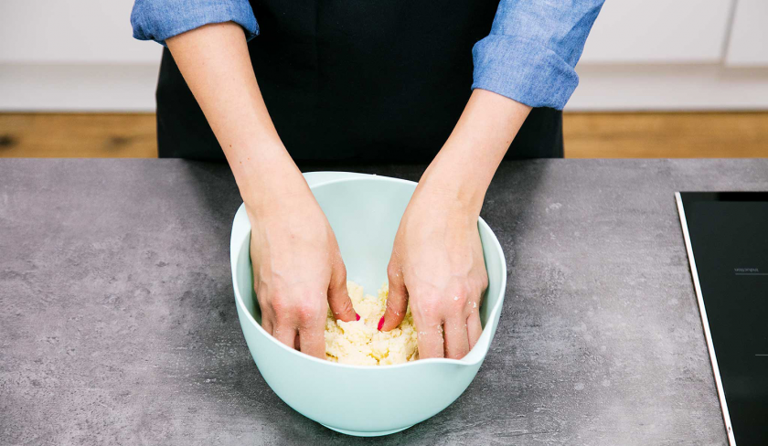 Für den Apfelkuchen mit Quark wird der Mürbeteig in einer Schüssel geknetet.