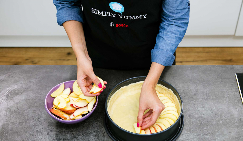 Die Obstspalten werden auf dem Boden von dem Apfelkuchen mit Quark verteilt.