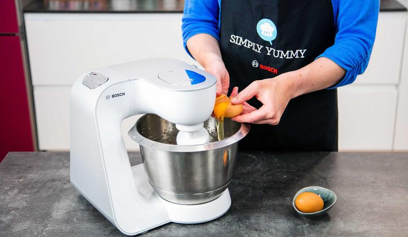 Für den Teig der Apfelmusmuffins wird ein Ei in die Rührschssel einer Küchenmaschine gegeben.
