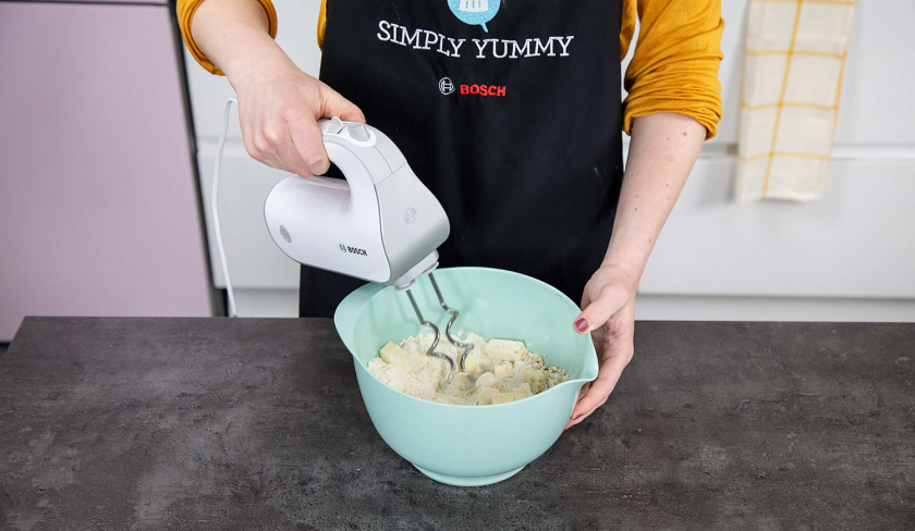Die Zutaten für den Aprikosenkuchen mit Streuseln werden mit einem Handrührgerät verknetet.