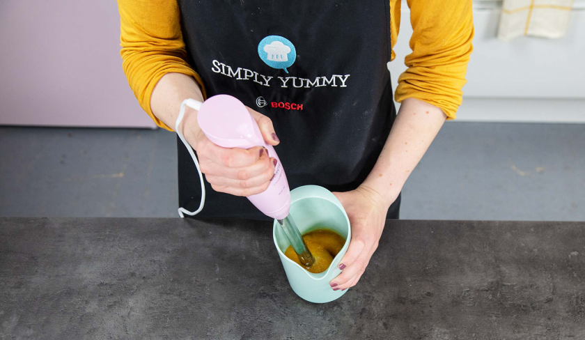 Aprikosen für den Aprikosenkuchen mit Streuseln werden mit einem Pürierstab püriert.