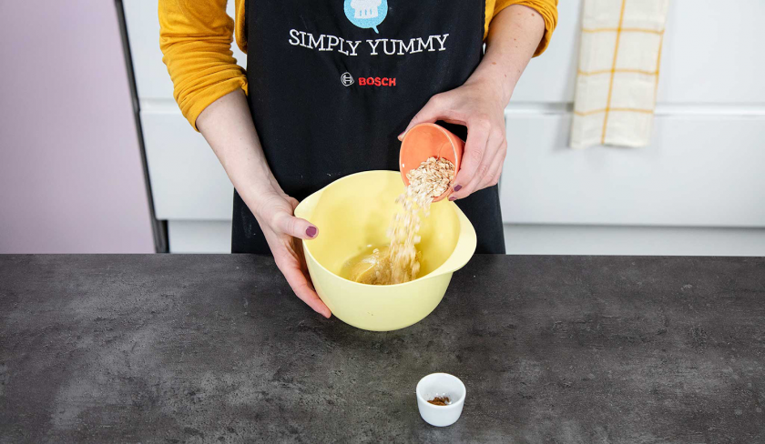Haferflocken werden in eine Schüssel mit Teig gegeben.