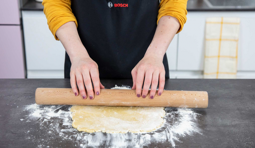 Der Mürbeteig für den Aprikosenkuchen mit Streuseln wird mit einem Nudelholz ausgerollt.