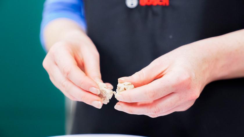 Hefe wird mit zwei Händen zerbröselt.