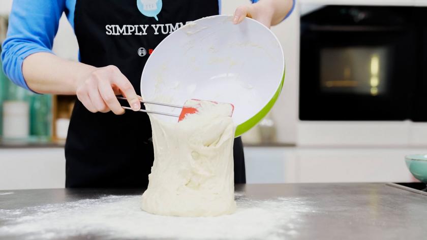 Der Teig für die Baguette Brötchen wird auf eine bemehlte Arbeitsfläche gegeben.