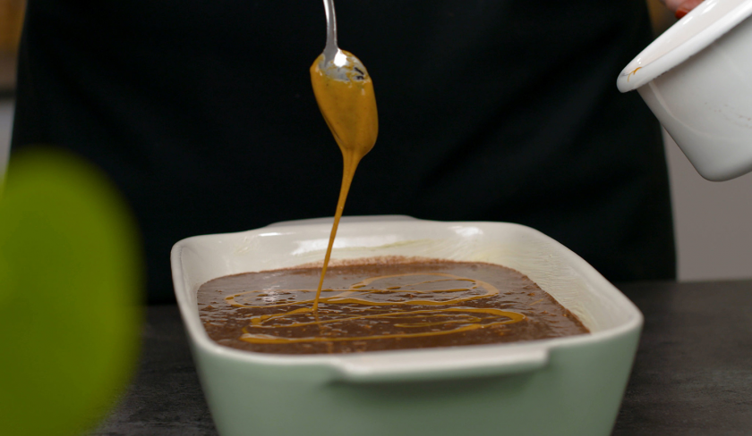 Erdnussbutter wird über dem Baked Oatmeal verteilt.