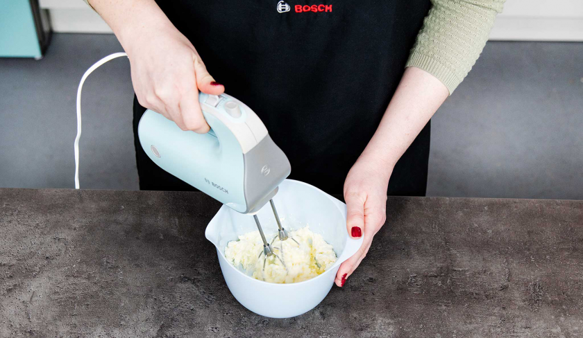 Für das Banana Bread mit Cheesecake-Swirl wird die Frischkäsecreme in einer Schüssel gemixt.
