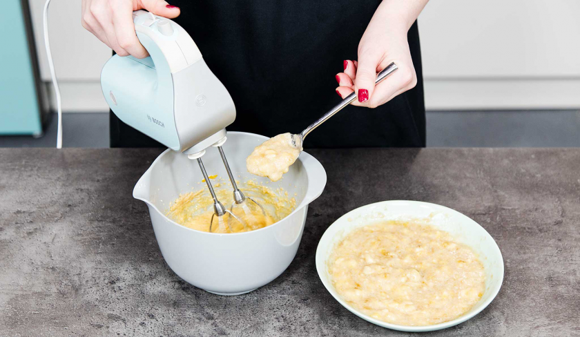 Bananenpüree wird unter den Teig für das Banana Bread mit Cheesecake-Swirl gemixt.