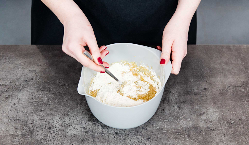 Es werden trockene Zutaten unter den Teig für das Banana Bread mit Cheesecake-Swirl gerührt.