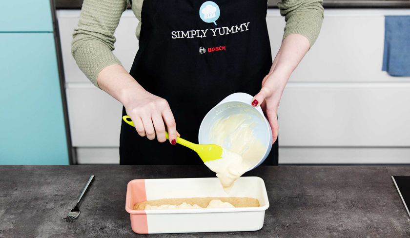 Die Frischkäsecreme wird auf den Teig in Form für das Banana Bread mit Cheesecake-Swirl gegeben.