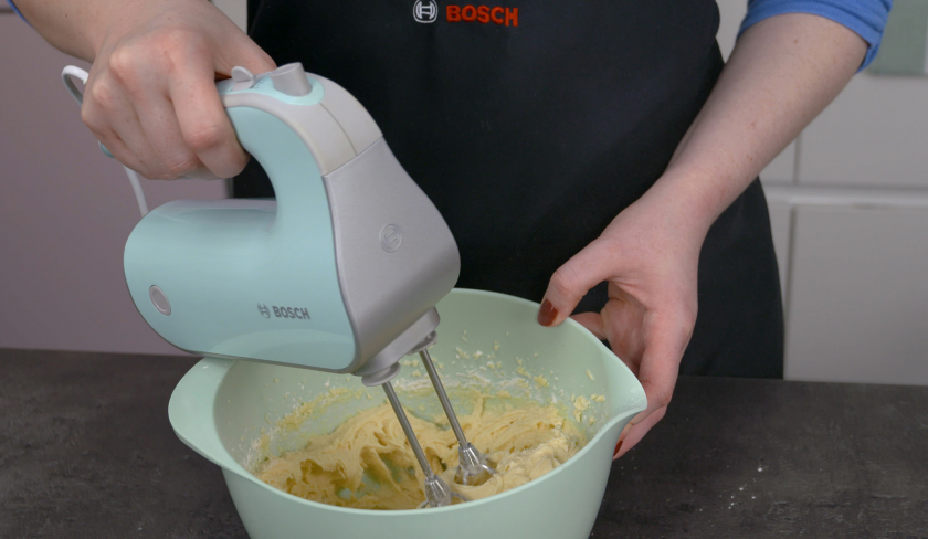 Der Teig von dem Birnenkuchen mit Knusperkruste wird in einer Rührschüssel mit einem Handmixer zubereitet.
