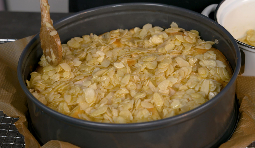 Die Mandelmasse für den Birnenkuchen mit Knusperkruste wird auf dem Kuchen verteilt.