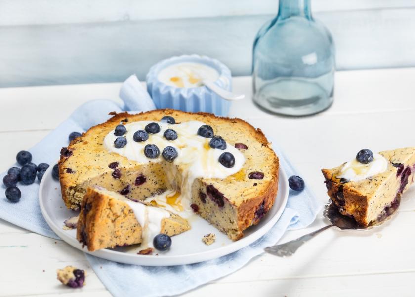 Angeschnittener Blaubeer-Mandelkuchen mit Joghurt.