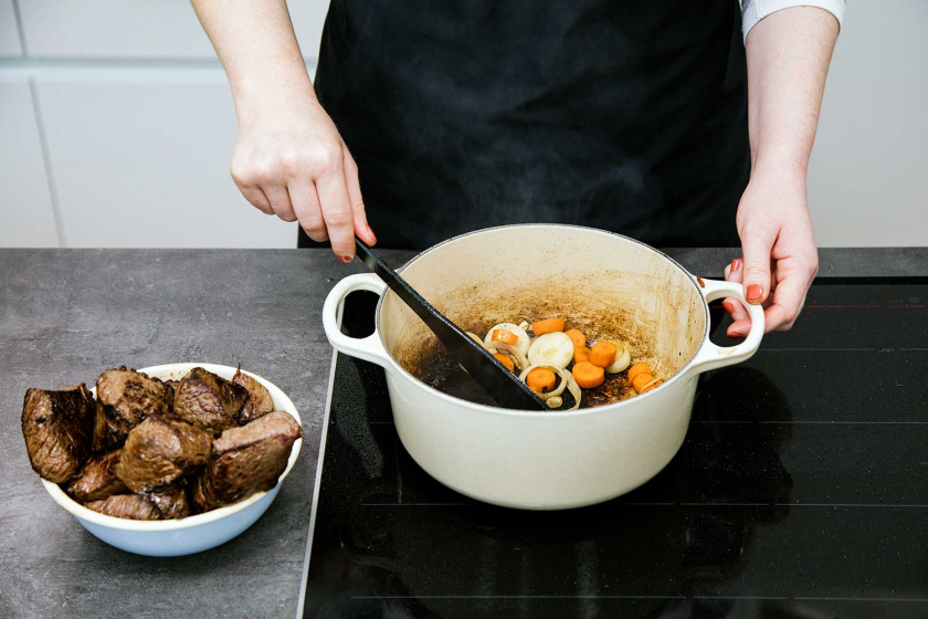 Gemüse für Boeuf Bourguignon wird in einem Bräter angebraten.