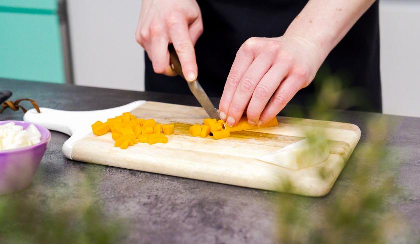 Für die Bolognese-Törtchen mit Knusperteig werden Möhren auf einem Holzbrett gewürfelt.