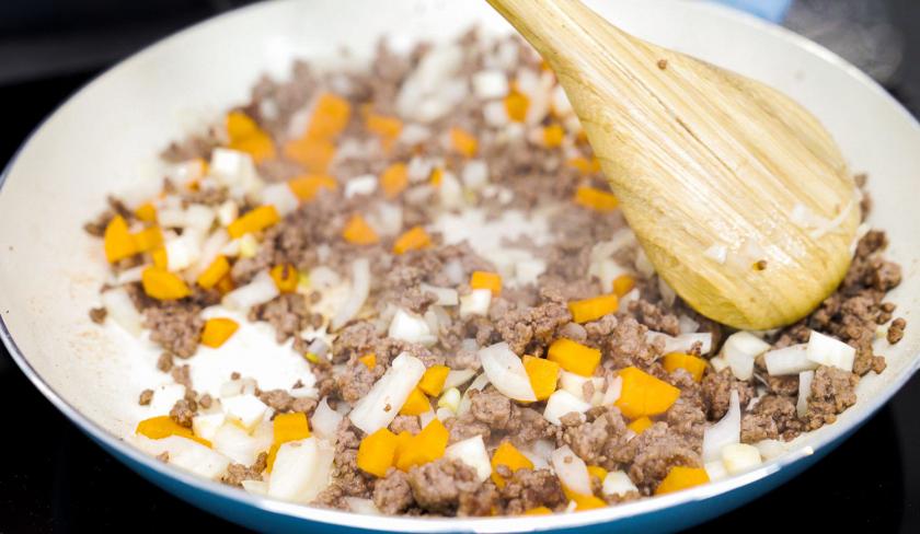 Für die Bolognese-Törtchen mit Knusperteig wird Hackfleisch mit Möhre in einer Pfanne angebraten.