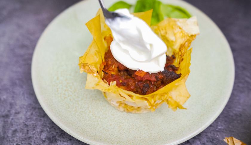 Die Bolognese-Törtchen mit Knusperteig werden mit einem Klecks Crème fraîche bedeckt.