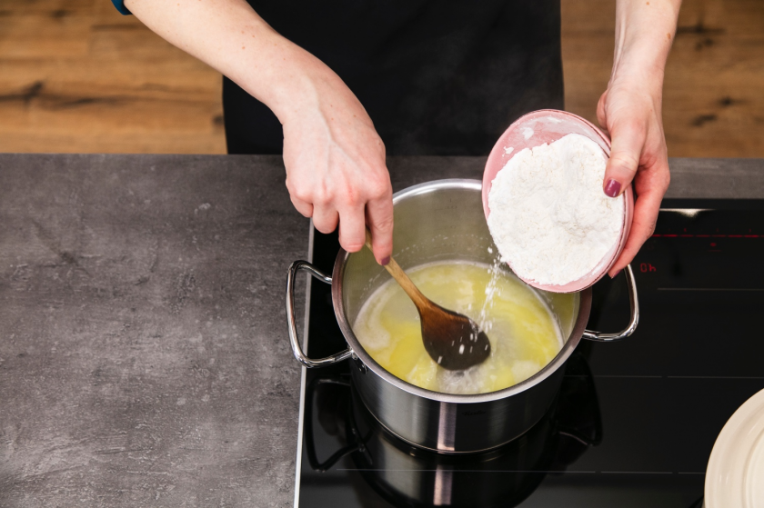 Für den Brandteig wird Stärke in den Topf zur Wasser-Butter-Mischung gegeben.