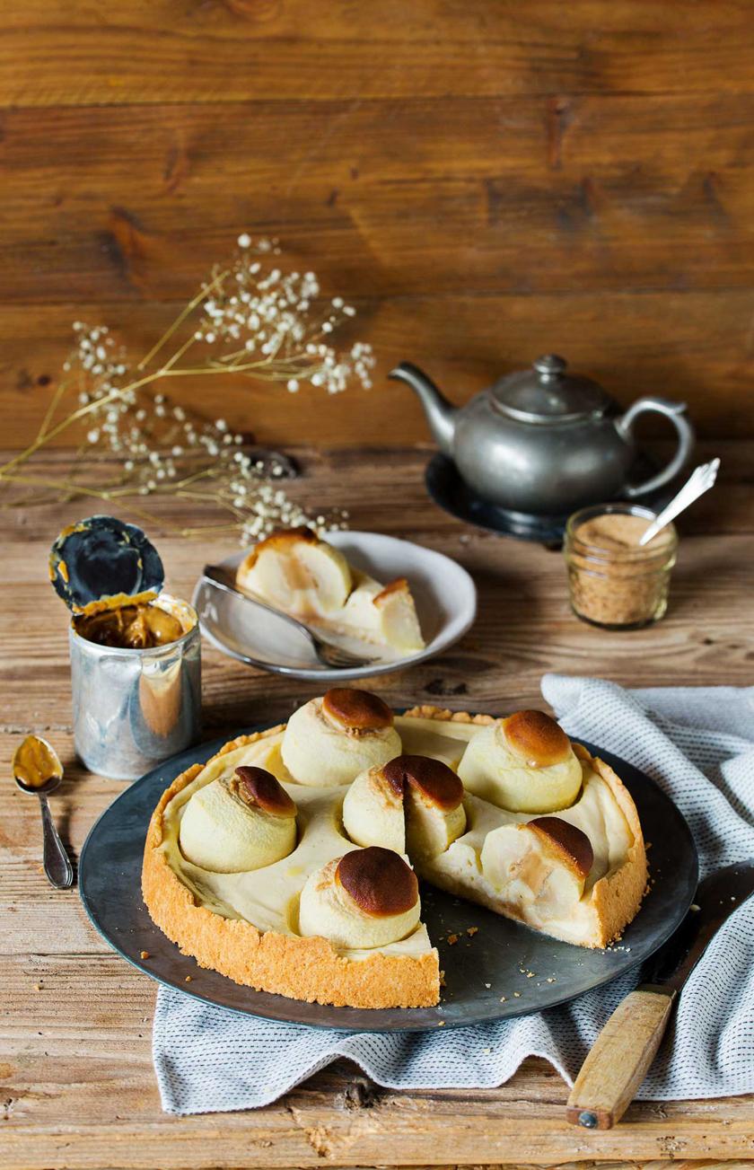 Bratapfel-Käsekuchen angeschnitten auf einem gedeckten Tisch.