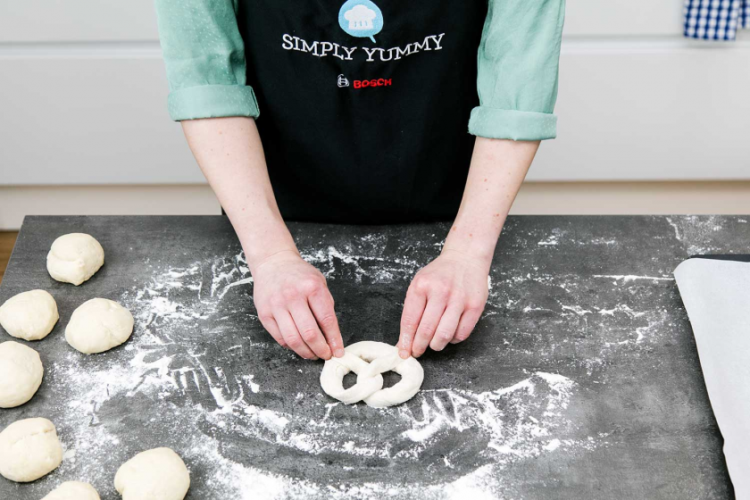 Die Enden der geformten Brezel werden seitlich am teig festgedrückt.