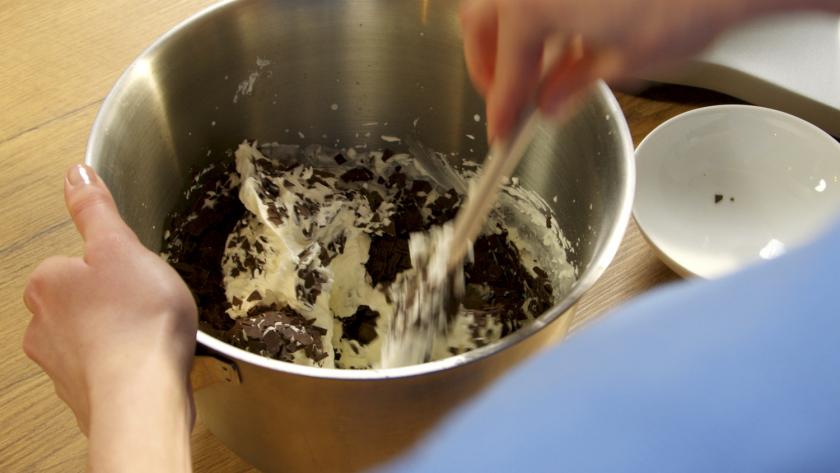 Schokoraspel werden unter aufgeschlagene Sahne gehoben.