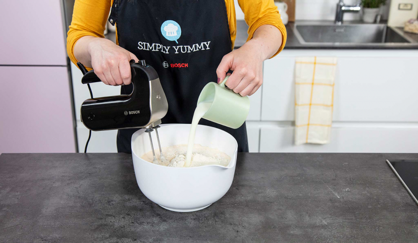 Trockene Zutaten und Sahne werden in einer Schüssel mit der Eiermasse zum Teig für den Buttermilchkuchen zusammengerührt.