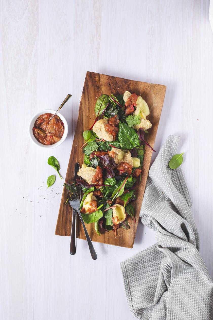 Panierter Camembert in Stücken auf Salat mit Chutney angerichtet.