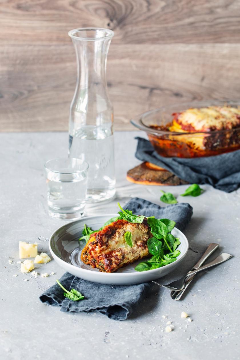 Auflaufform und Teller mit Cannelloni mit Spinat-Ricotta-Füllung.