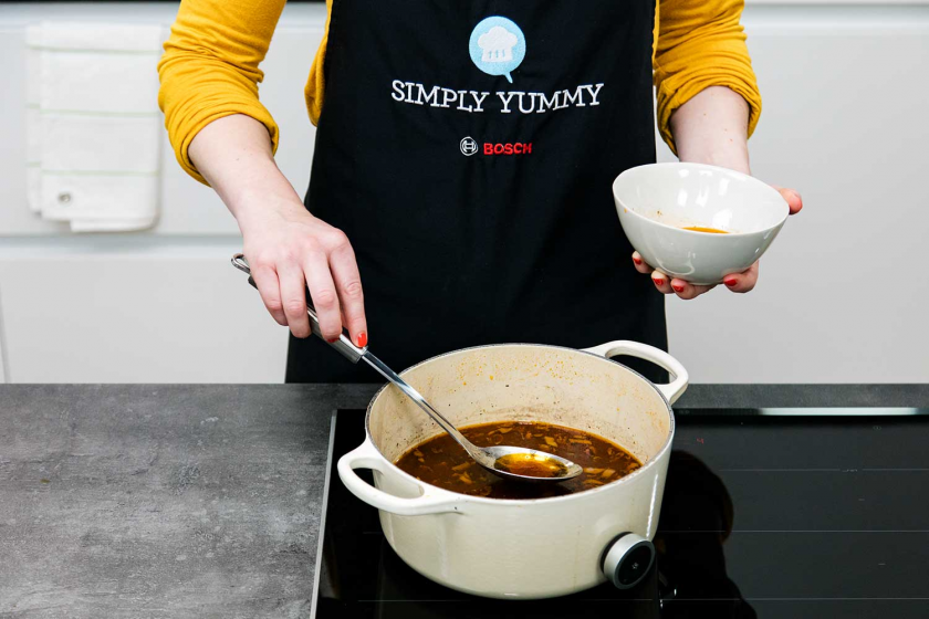 ie Soße für das Coq au Vin wird mit einem Löffel von Fett befreit.