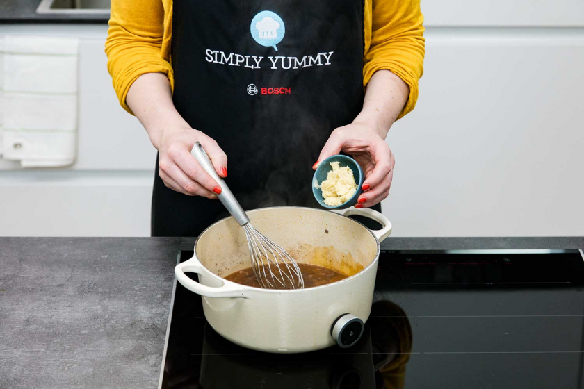 Zur Soße für das Coq au Vin wird Butter gegeben.