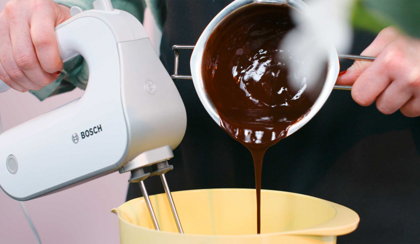 Geschmolzene Schokolade wird zum Teig von den Crème Brulée Brownie Törtchen gerührt.